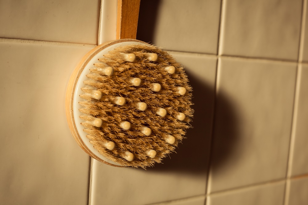 Shower brush in the bathroom against a tiled wall in the morning sunlight