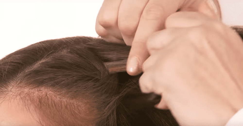 Hairstylist starting French braid in model's hair