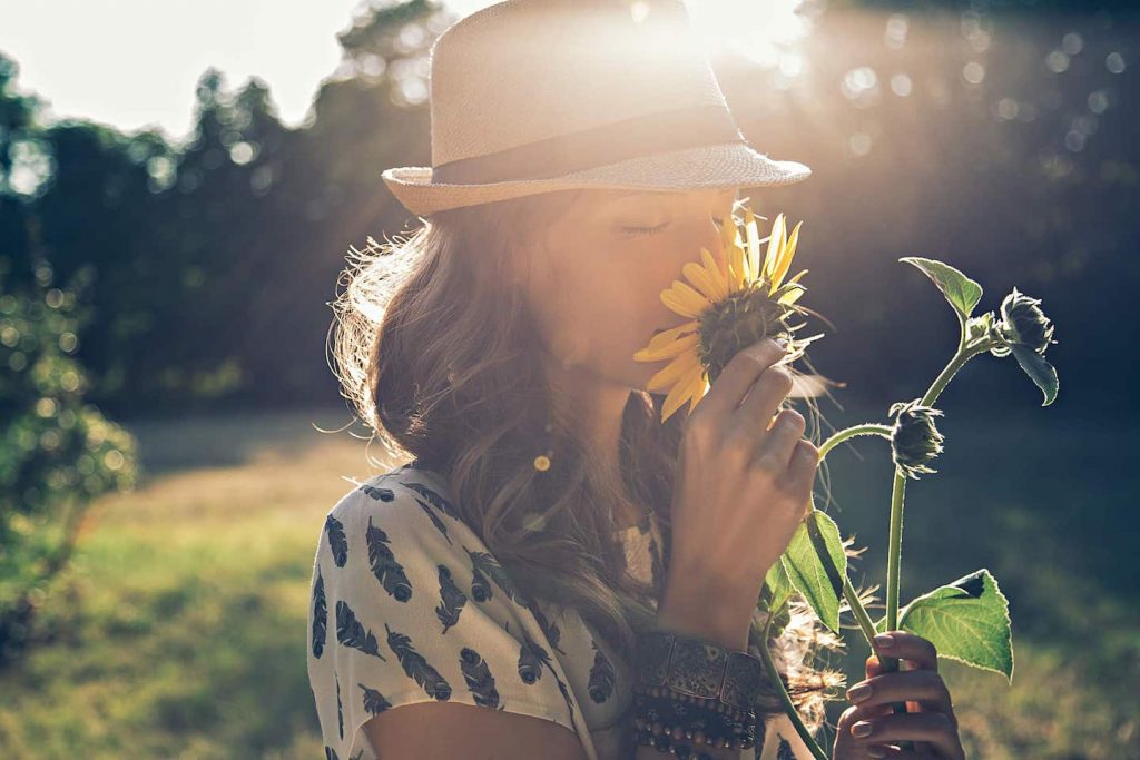 Girl smells sunflower in nature