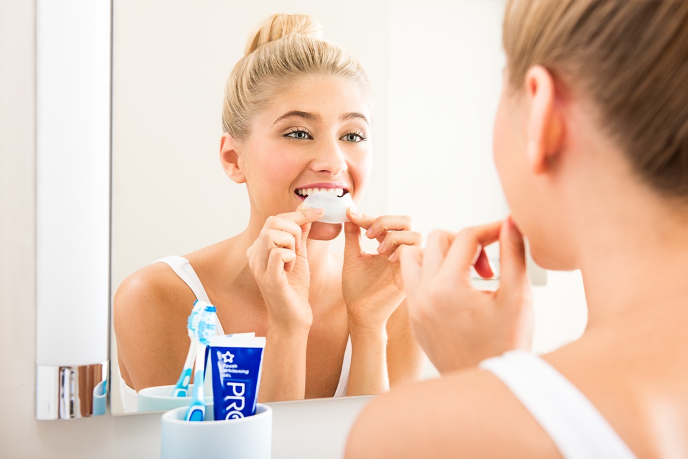 Female applying teeth whitening strips