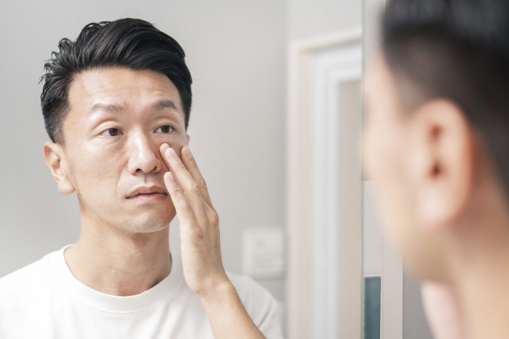 Male model touching his face and looking in mirror