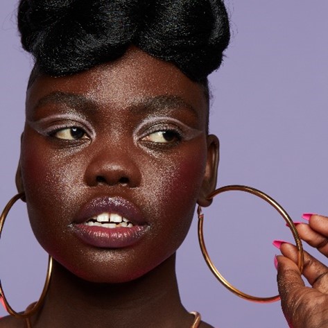 Black female with makeup on holding hoop earring