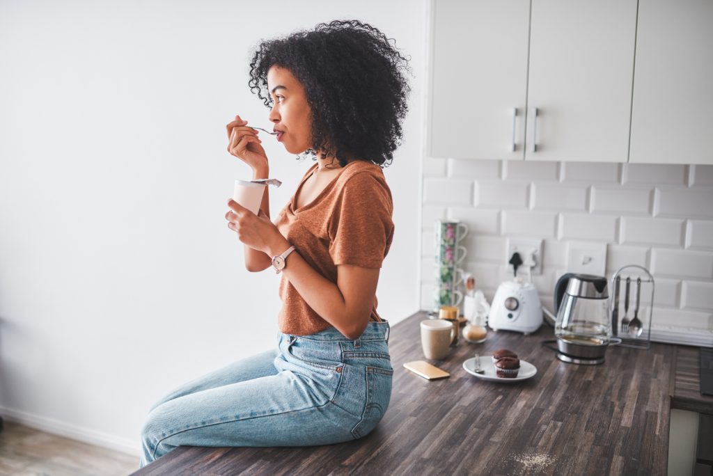 Female sitting in kitchen eating healthy snacks