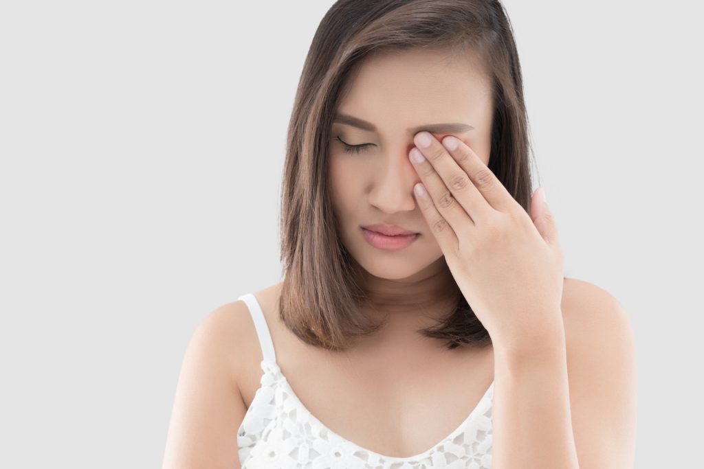 Female holding eye suffering with eye pain