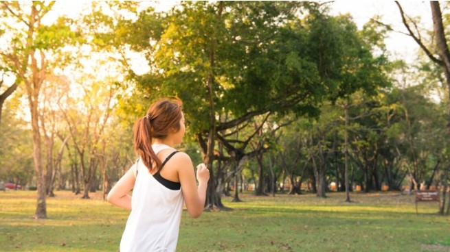 Female running through park with trees