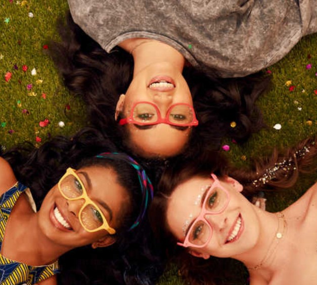 3 females wearing colourful spectacles laid on grass
