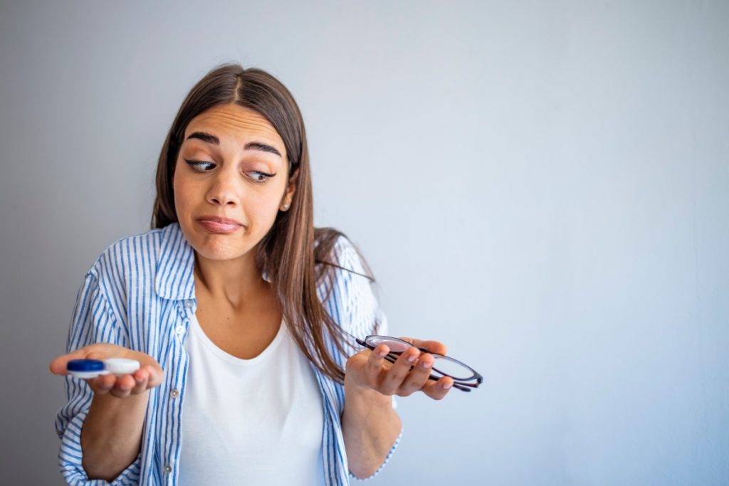 Female choosing between spectacles or contact lenses