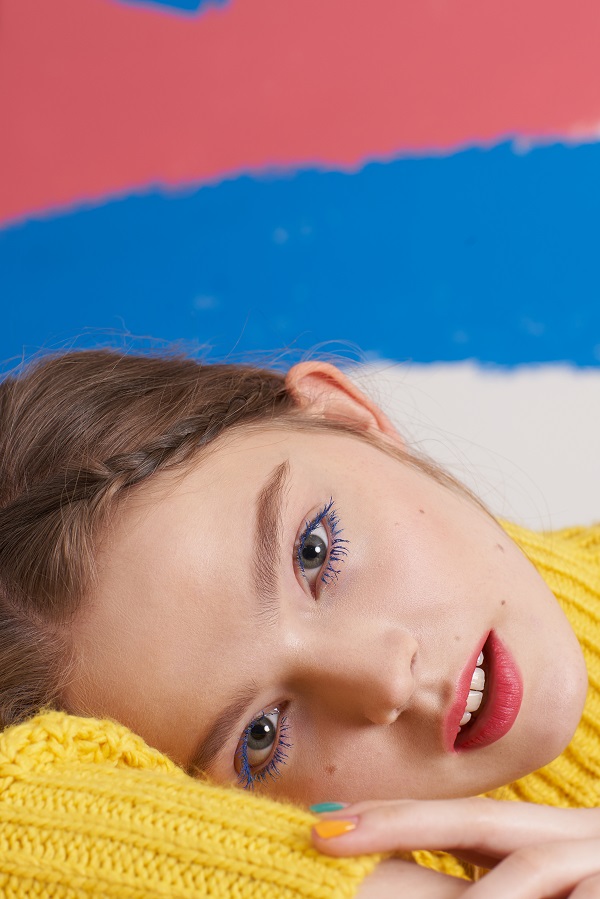 Girl looking at camera wearing makeup with coloured background