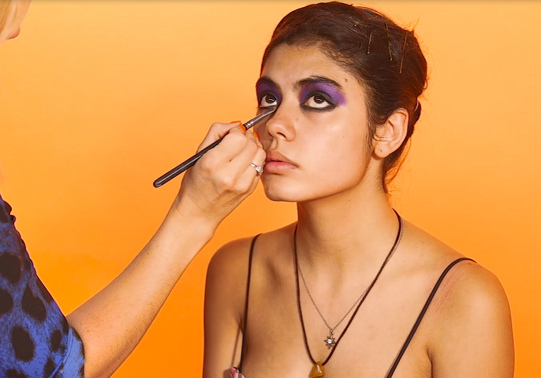 MUA applying dark eyeshadow to model