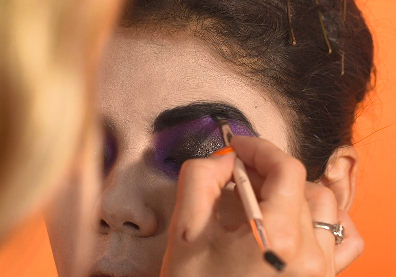 MUA adding black pomade to model's brows