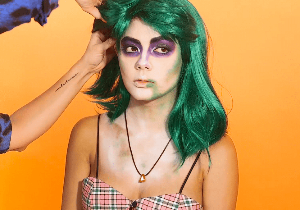 MUA adding a green wig to model to create a Beetlejuice makeup look