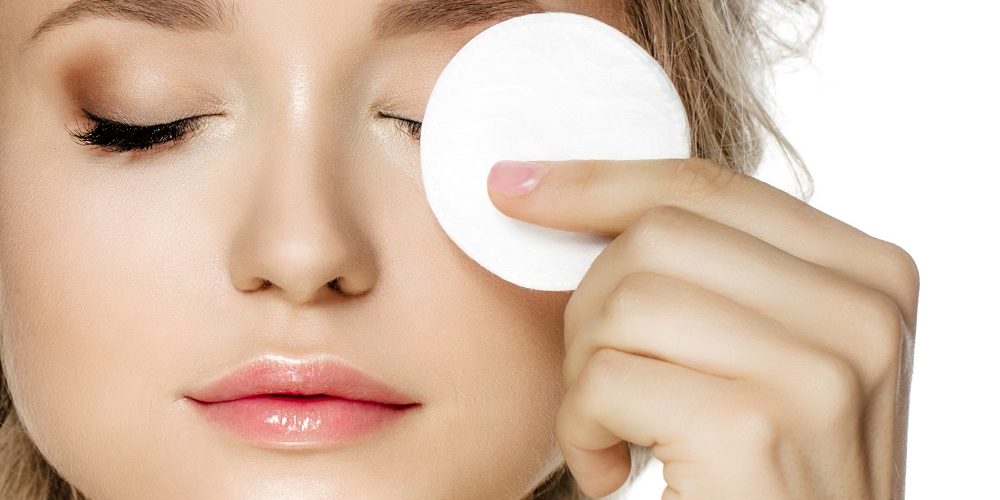 Young model cleaning face with cotton pad, skin care