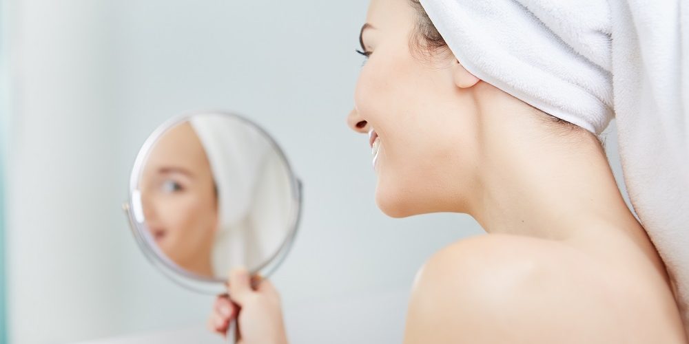 face of young beautiful healthy woman and reflection in the mirror