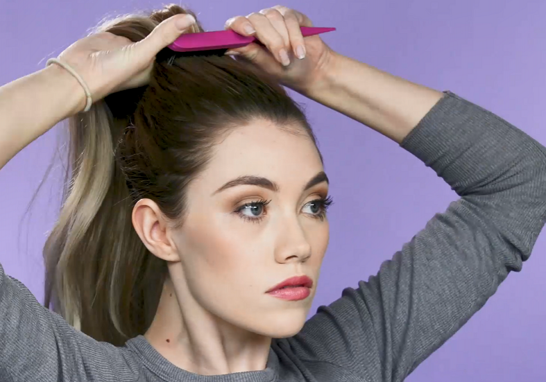 Woman brushing hair into ponytail