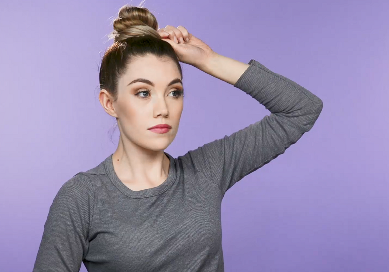 Women styling hair into top knot