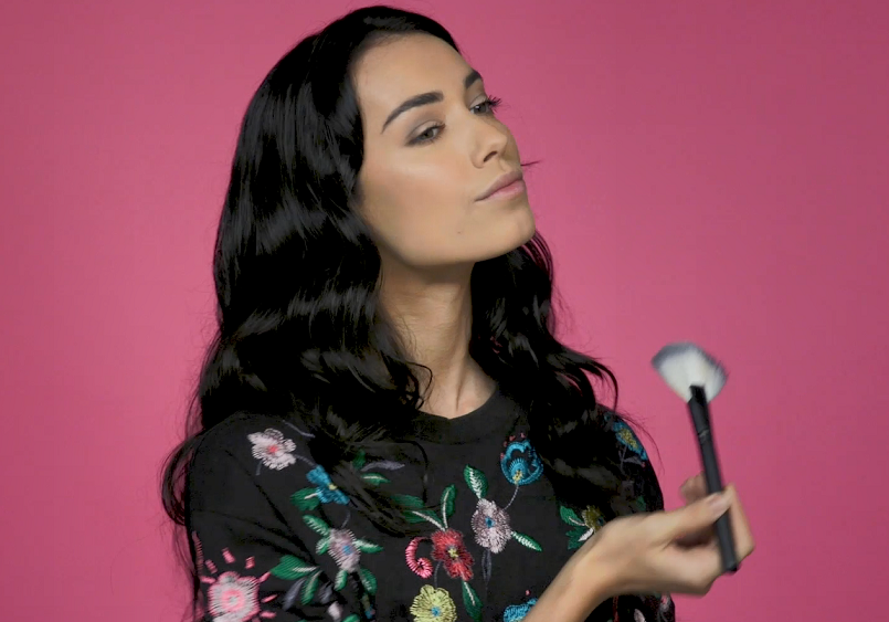 Woman applying highlighter to cheeks with fan brush