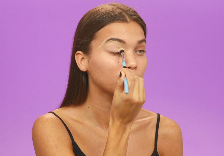 Model adding concealer around brows