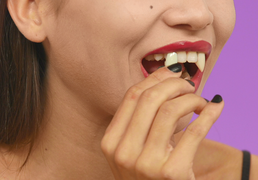 Model adding vampire fangs to teeth to create a vampire Halloween look