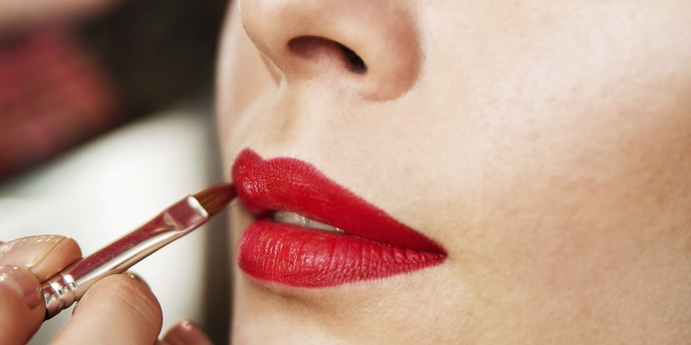 Applying red lipstick using lip brush