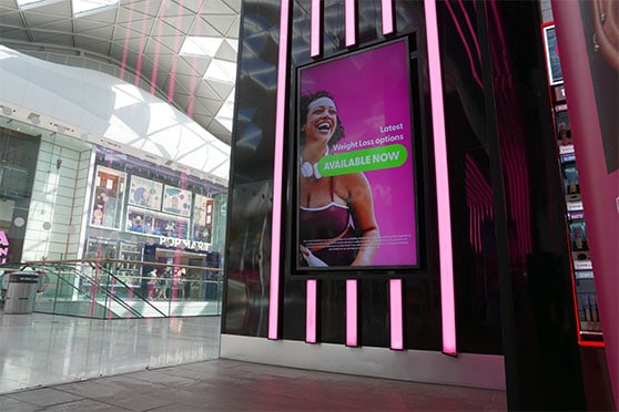 Optimo in-store screen positioned near a Superdrug window.